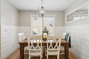 Dining space featuring hardwood / wood-style flooring, wood walls, and a notable chandelier