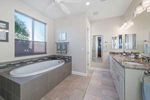 Bathroom featuring tile patterned flooring, vanity, and a relaxing tiled tub