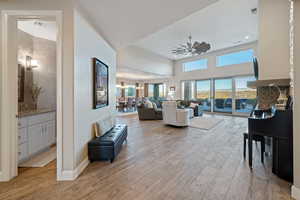 Living room with sink, ceiling fan with notable chandelier, light hardwood / wood-style flooring, and a high ceiling