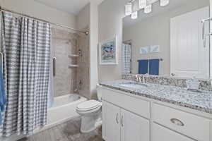 Full bathroom featuring shower / bath combination with curtain, vanity, and toilet