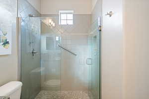 Bathroom featuring toilet and a shower with shower door