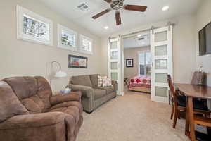 Living room with a barn door, light carpet, and ceiling fan