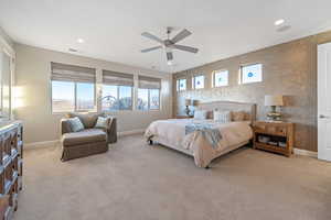 Carpeted bedroom featuring ceiling fan and multiple windows