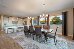 Dining room with sink, a chandelier, and light wood-type flooring