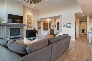 Living room with light hardwood / wood-style flooring, ceiling fan, and a high ceiling