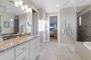 Bathroom featuring ceiling fan, vanity, and independent shower and bath