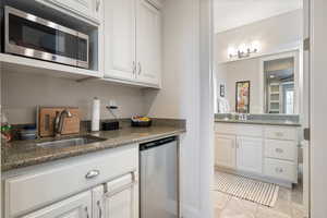 Kitchen with stainless steel appliances, stone countertops, sink, and white cabinets