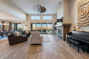 Living room featuring a towering ceiling, ceiling fan with notable chandelier, a healthy amount of sunlight, and light wood-type flooring