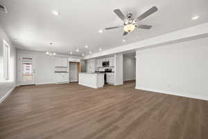 Unfurnished living room with sink, hardwood / wood-style flooring, and ceiling fan with notable chandelier