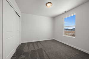 Unfurnished bedroom with dark colored carpet, a mountain view, and a closet