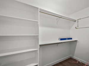 Spacious closet with dark hardwood / wood-style flooring and secured water heater