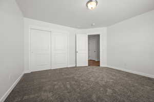 Unfurnished bedroom featuring dark colored carpet and a closet