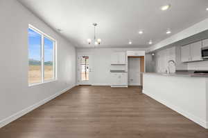 Unfurnished living room with dark hardwood / wood-style floors, sink, and a notable chandelier