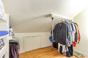 Spacious walk in closet featuring lofted ceiling and light hardwood floors