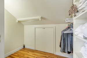 Spacious walk in closet featuring built in shelving and light hardwood floors