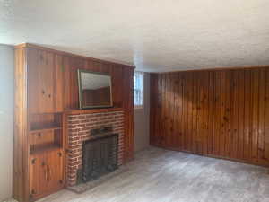 Basement/ADU living room with a fireplace, a laminate flooring, and wood walls.