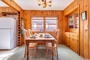 Dining area with a notable chandelier, knotty pine walls, and ornamental molding