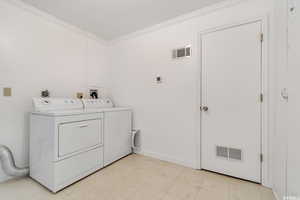 Laundry room with crown molding and washer and dryer