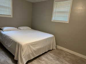 Bedroom with laminate flooring and a textured ceiling.