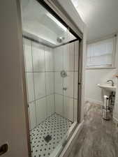 Bathroom featuring hardwood / wood-style flooring, a shower with door, and a textured ceiling