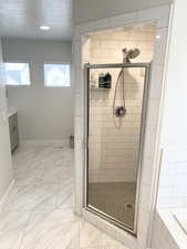 Bathroom with vanity, shower with separate bathtub, and a textured ceiling