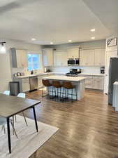 Kitchen featuring a kitchen island, appliances with stainless steel finishes, a breakfast bar, hardwood / wood-style floors, and grey cabinets