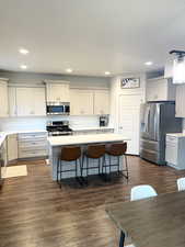 Kitchen featuring grey cabinetry, stainless steel appliances, a center island, and a breakfast bar area