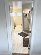 Bathroom featuring a textured ceiling and a shower with shower door