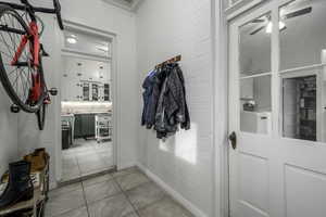 Interior space with ceiling fan, brick wall, separate washer and dryer, and light tile patterned floors