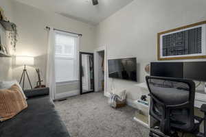 Carpeted office space featuring lofted ceiling and ceiling fan