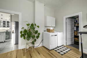 Laundry area featuring light hardwood / wood-style floors, cabinets, and washing machine and clothes dryer