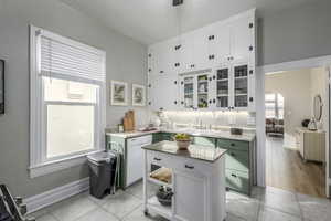 Kitchen with light tile patterned flooring, dishwasher, sink, and white cabinets