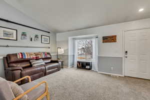 Carpeted living room featuring vaulted ceiling