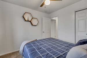 Carpeted bedroom with ceiling fan and a closet