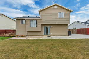 Rear view of property featuring a lawn and a patio area