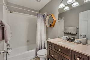 Full bathroom featuring vanity, shower / tub combo with curtain, and toilet