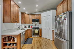 Kitchen featuring lofted ceiling, stainless steel appliances, sink, and light wood-type flooring