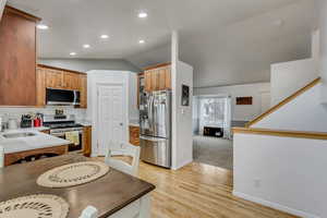 Kitchen featuring lofted ceiling, sink, stainless steel appliances, and light wood-type flooring