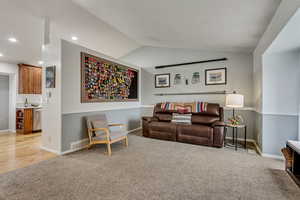 Carpeted living room featuring lofted ceiling