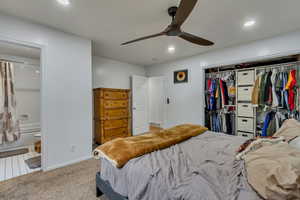 Carpeted bedroom featuring connected bathroom, a closet, and ceiling fan