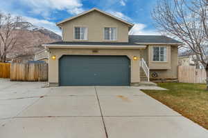 View of front of property with a mountain view, a garage, and a front lawn