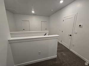 Hallway featuring dark colored carpet