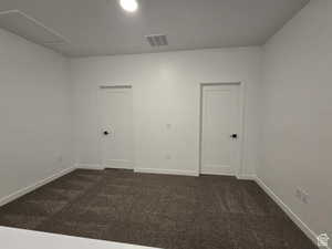 Empty room featuring dark colored carpet