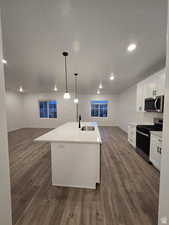 Kitchen featuring white cabinetry, sink, a center island with sink, and appliances with stainless steel finishes