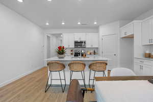 Kitchen featuring a kitchen island with sink, white cabinetry, and stainless steel appliances