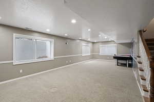 Basement with light colored carpet and a textured ceiling