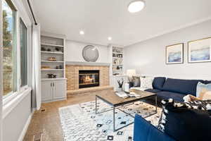 Carpeted living room with crown molding, a brick fireplace, and built in features