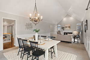 Dining area featuring light carpet, crown molding, lofted ceiling, and a premium fireplace