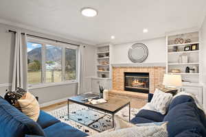 Living room with crown molding, a brick fireplace, a mountain view, and built in shelves