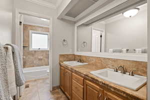 Full bathroom with decorative backsplash, tiled shower / bath combo, ornamental molding, vanity, and toilet